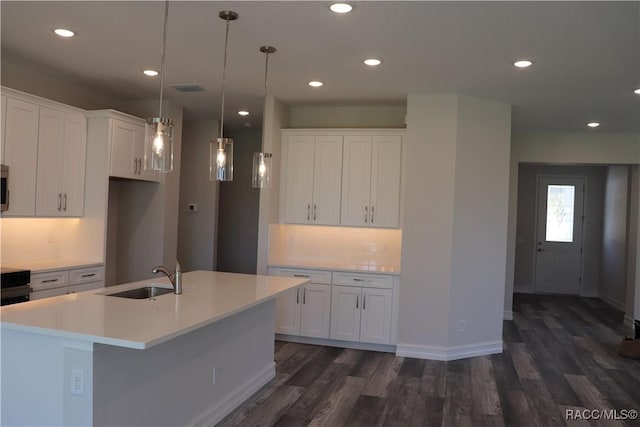 kitchen featuring dark wood-style floors, light countertops, decorative backsplash, white cabinetry, and a sink