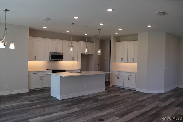 kitchen with white cabinets, stainless steel microwave, and visible vents