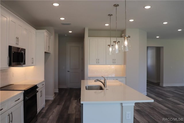 kitchen featuring black range with electric cooktop, visible vents, stainless steel microwave, and white cabinets