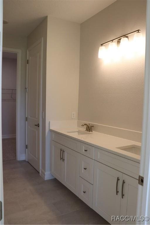 bathroom featuring double vanity, a closet, and a sink