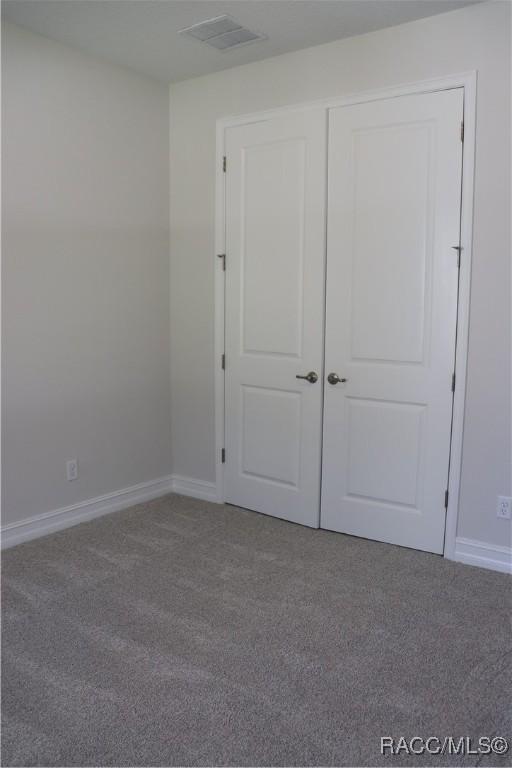 unfurnished bedroom featuring carpet, visible vents, and baseboards