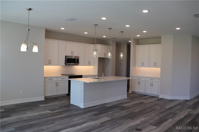 kitchen featuring dark wood finished floors, stainless steel microwave, visible vents, white cabinetry, and a sink