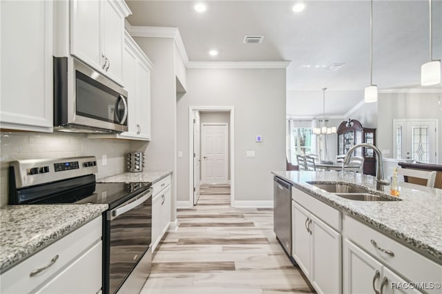 kitchen featuring sink, white cabinetry, hanging light fixtures, appliances with stainless steel finishes, and light stone countertops