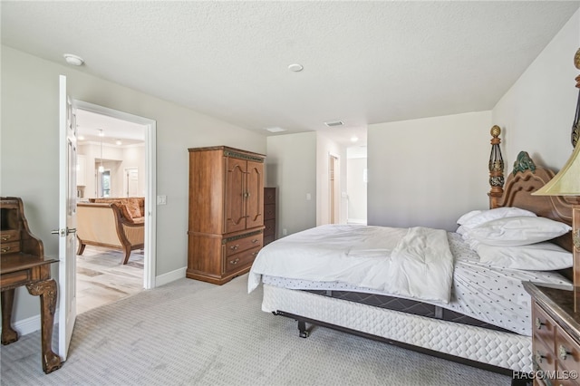 bedroom featuring ensuite bathroom, light carpet, and a textured ceiling