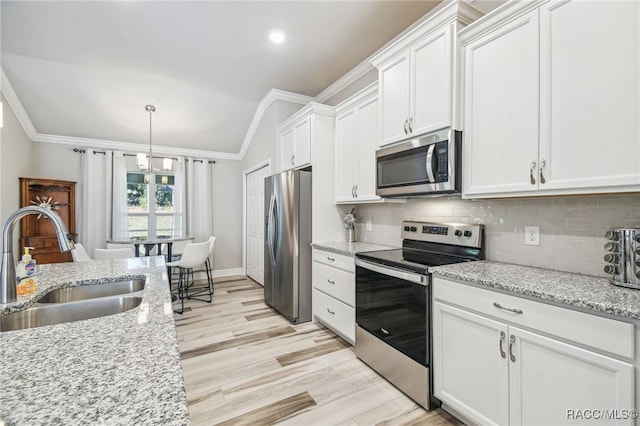 kitchen featuring sink, white cabinetry, ornamental molding, appliances with stainless steel finishes, and light stone countertops