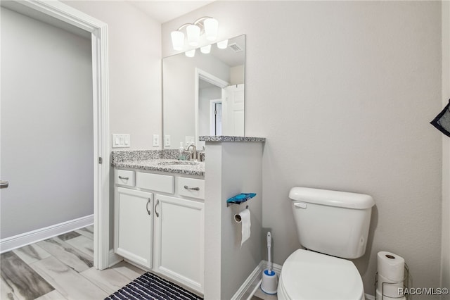 bathroom featuring vanity, wood-type flooring, and toilet