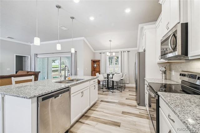 kitchen with decorative light fixtures, sink, appliances with stainless steel finishes, and an island with sink