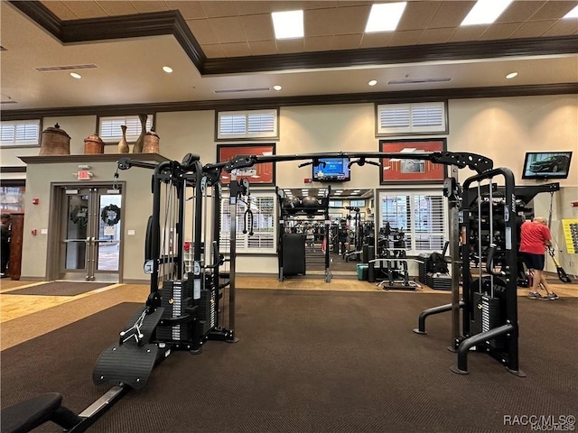 gym with a raised ceiling and crown molding