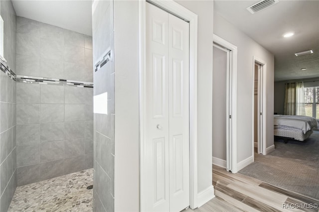 bathroom featuring hardwood / wood-style flooring and a tile shower