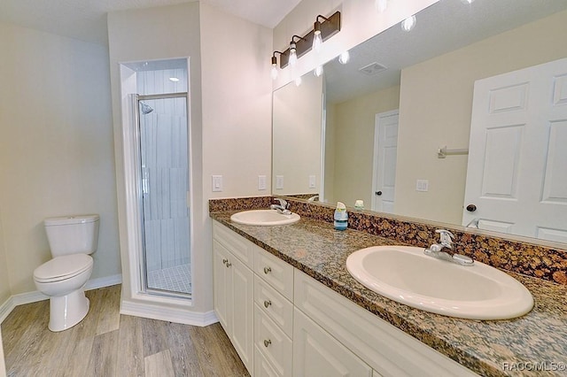 bathroom with toilet, hardwood / wood-style floors, a shower with door, and vanity