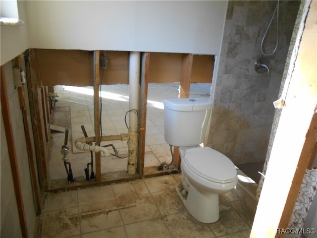 bathroom with a tile shower and toilet