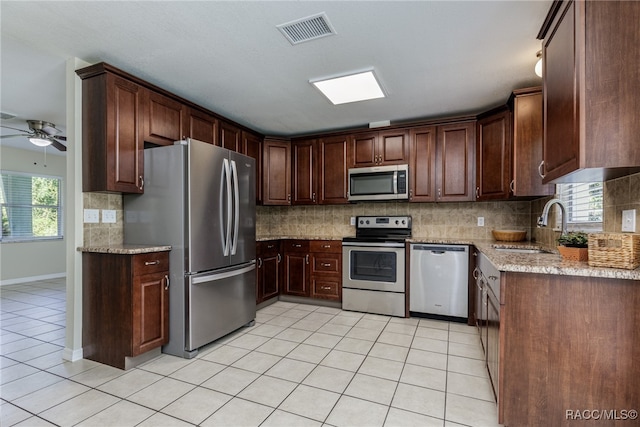 kitchen featuring sink, plenty of natural light, light stone counters, and appliances with stainless steel finishes