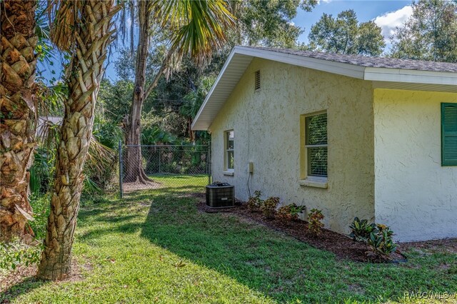 view of side of property with a yard and central AC unit