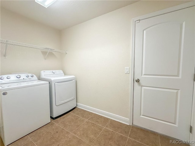 laundry room featuring laundry area, light tile patterned flooring, washer and clothes dryer, and baseboards