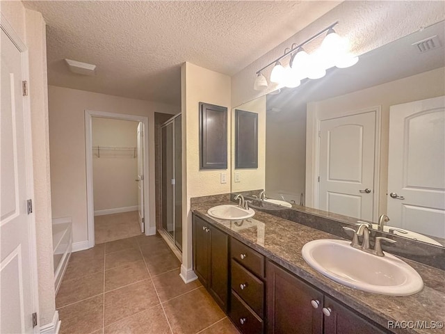 bathroom with a walk in closet, double vanity, a sink, and tile patterned floors