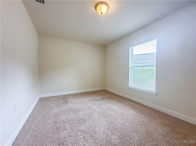 unfurnished room featuring carpet flooring, visible vents, and baseboards