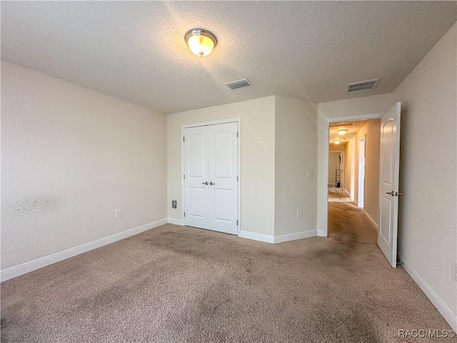 unfurnished bedroom with a closet, a textured ceiling, and carpet