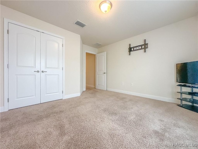 unfurnished bedroom with a closet, visible vents, baseboards, and carpet flooring