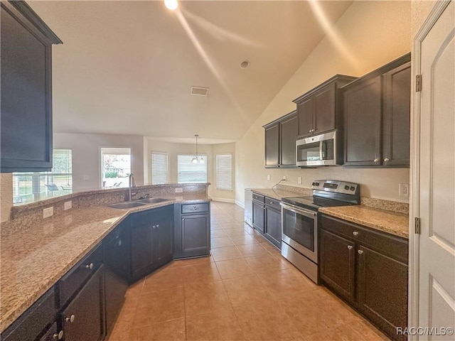 kitchen with lofted ceiling, sink, light tile patterned floors, pendant lighting, and appliances with stainless steel finishes