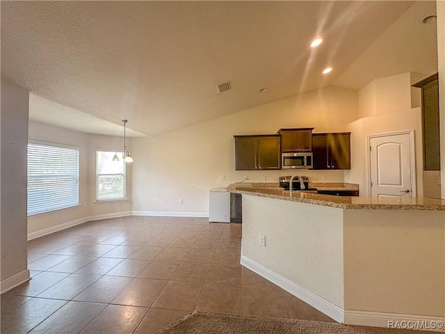 kitchen with light stone counters, vaulted ceiling, tile patterned floors, and appliances with stainless steel finishes