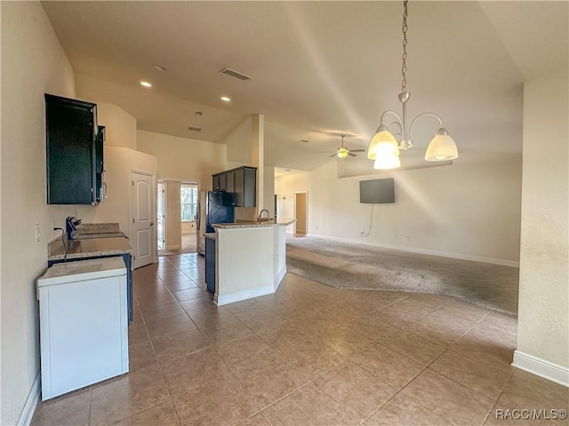 kitchen featuring lofted ceiling, decorative light fixtures, stainless steel fridge, light stone countertops, and ceiling fan with notable chandelier