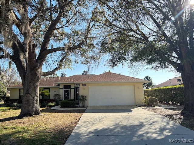 ranch-style house featuring a garage, concrete driveway, and stucco siding