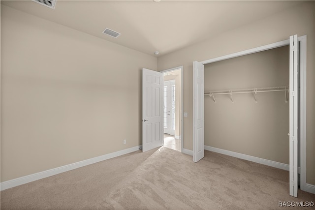 unfurnished bedroom featuring light carpet and a closet