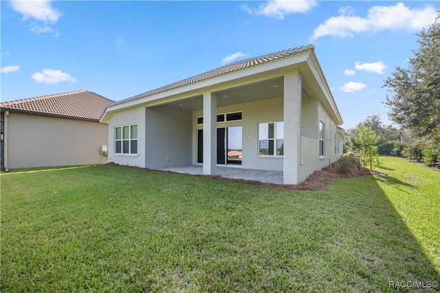 rear view of house featuring a yard and a patio