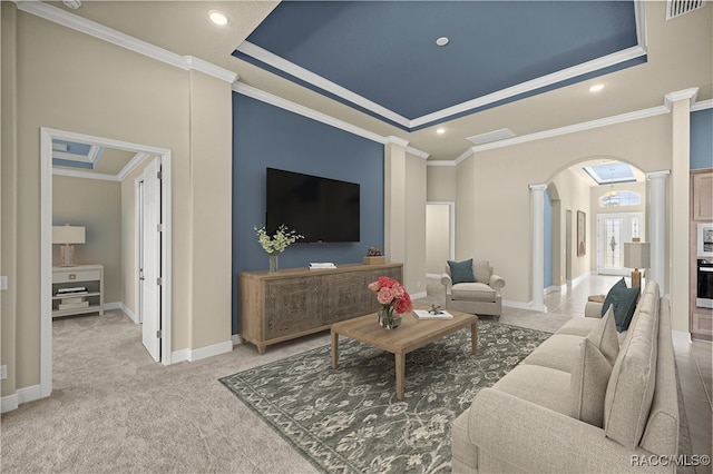 carpeted living room featuring ornamental molding, a tray ceiling, and decorative columns