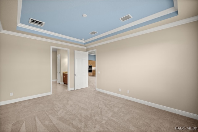 carpeted spare room featuring a tray ceiling and crown molding