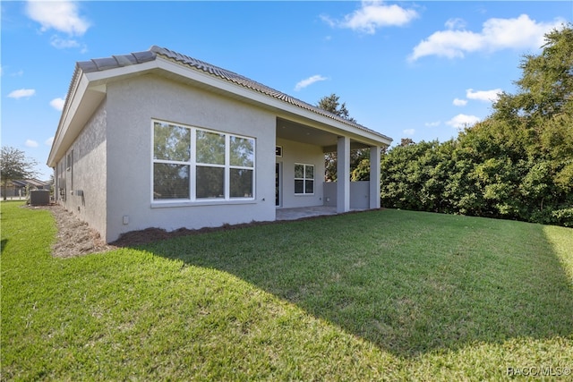 back of house featuring a patio area and a lawn