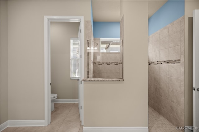 bathroom with a tile shower, tile patterned flooring, and toilet