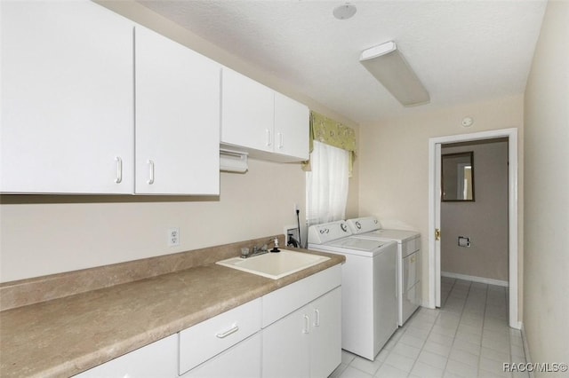 laundry room with a textured ceiling, cabinets, washing machine and clothes dryer, and sink