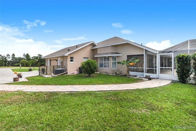 back of house with a lanai, central AC unit, and a lawn