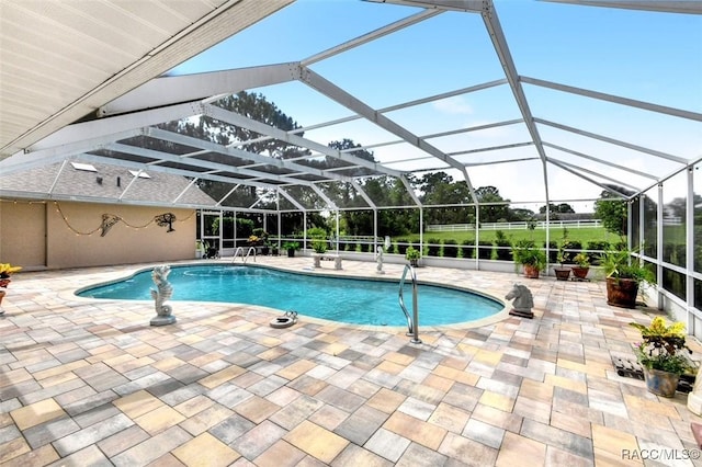 view of pool with glass enclosure and a patio