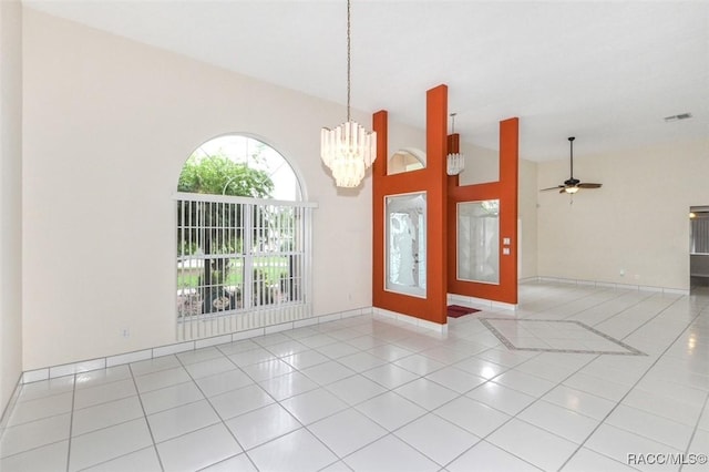 tiled spare room with a towering ceiling, ceiling fan with notable chandelier, and french doors