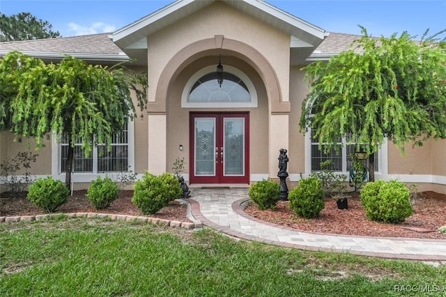 view of exterior entry featuring french doors and a lawn