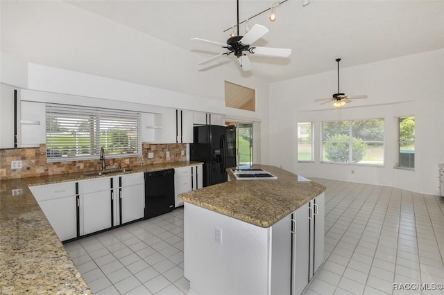 kitchen with backsplash, black appliances, sink, white cabinetry, and light stone counters