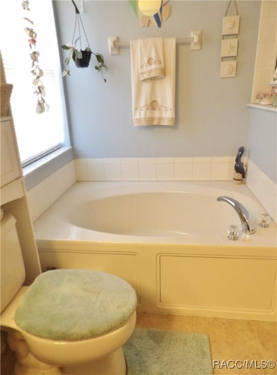 bathroom featuring a tub, tile patterned floors, and toilet