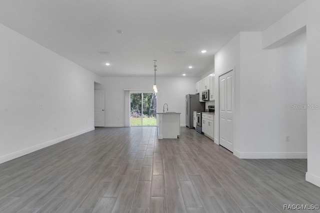 unfurnished living room featuring light wood-type flooring and sink