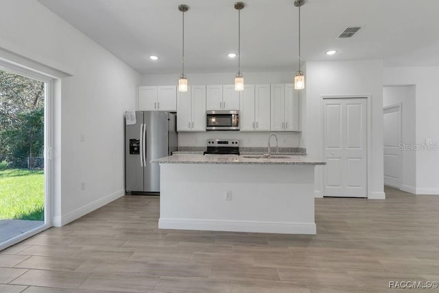 kitchen with light stone countertops, appliances with stainless steel finishes, and white cabinetry