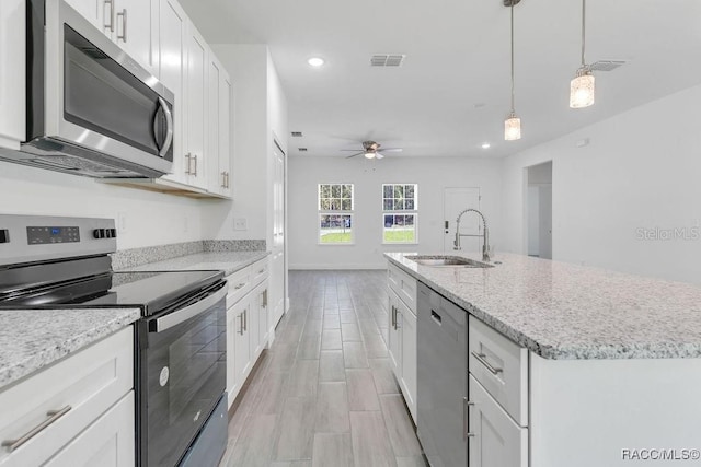 kitchen with white cabinets, sink, ceiling fan, an island with sink, and stainless steel appliances