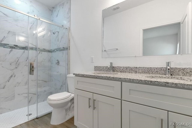 bathroom featuring a shower with door, vanity, wood-type flooring, and toilet