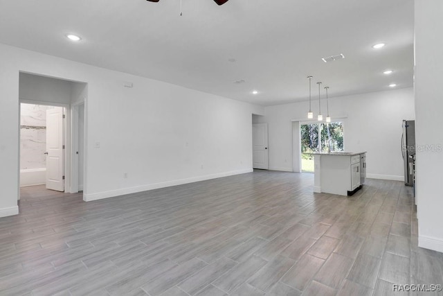 unfurnished living room featuring ceiling fan and light wood-type flooring