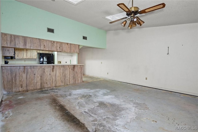 interior space featuring ceiling fan, a high ceiling, a textured ceiling, black fridge, and kitchen peninsula