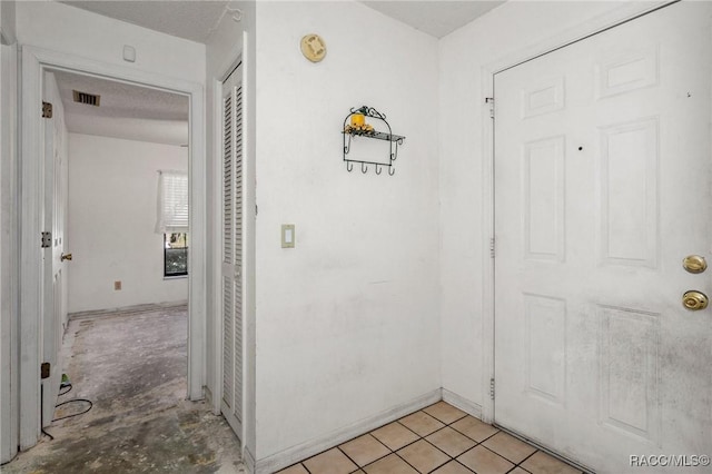 hall featuring light tile patterned floors and a textured ceiling