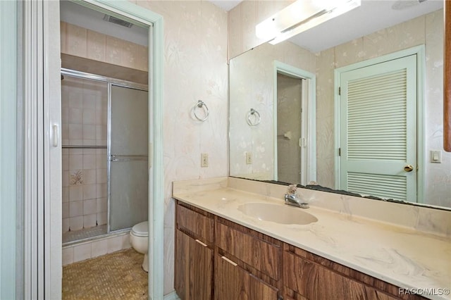 bathroom with vanity, toilet, tile patterned flooring, and a shower with door