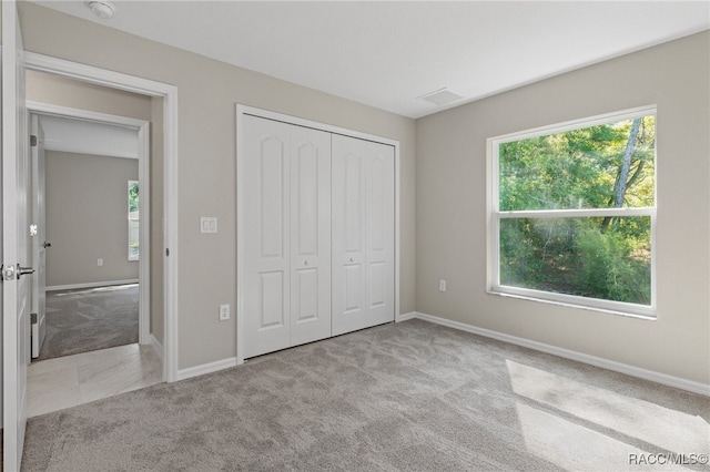 unfurnished bedroom with light colored carpet and a closet