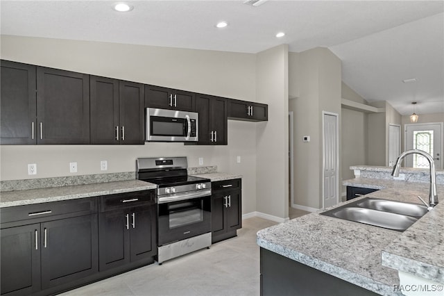 kitchen featuring light stone counters, sink, vaulted ceiling, and appliances with stainless steel finishes