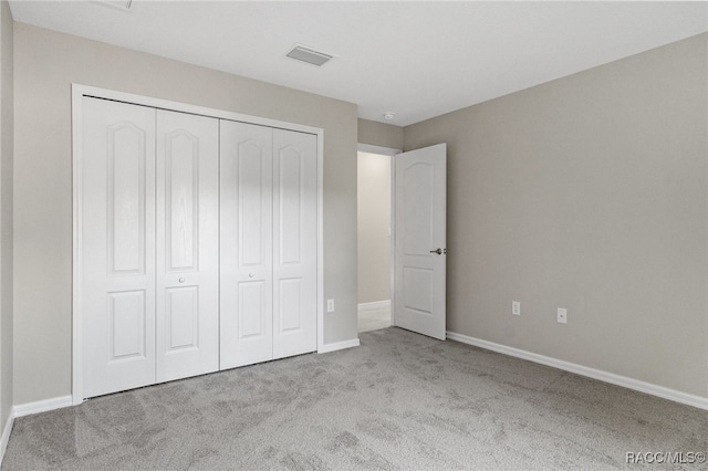 unfurnished bedroom featuring light carpet and a closet